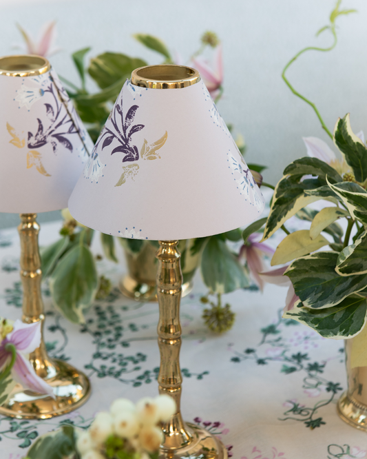 Maharani candle shade on brass tealight stand amongst green flower arrangements on botanica linen tablecloth