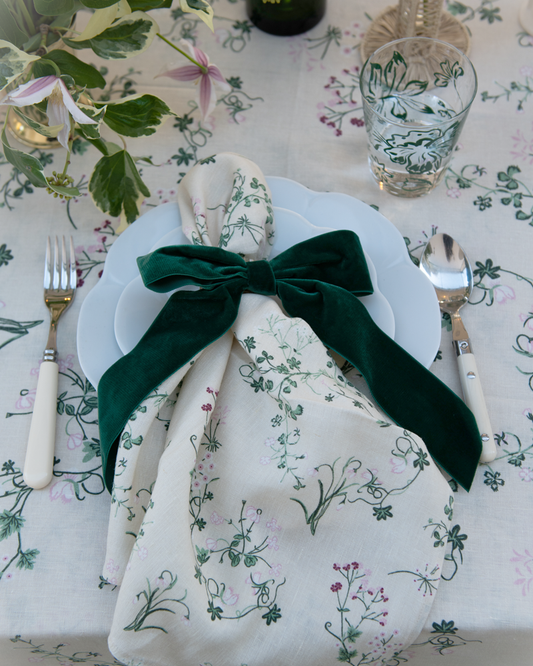 Botanica linen tablecloth and napkin setting with green velvet decorative bow on napkin ring